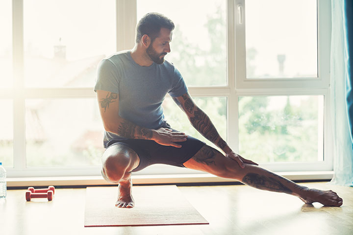 man stretching at home with fitness mat 